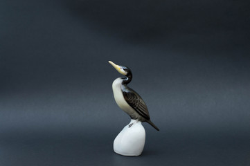 Porcelain cormorant figurine on black background