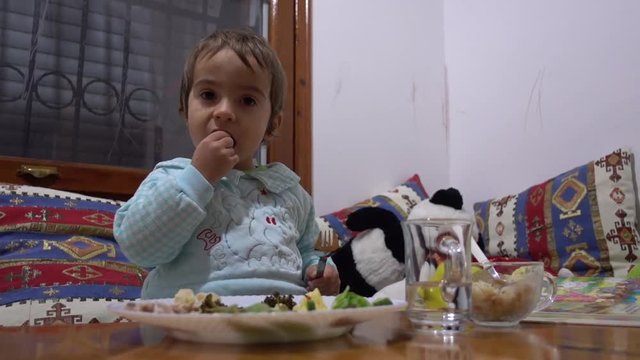 Child eats and tastes an olive at the dinner table