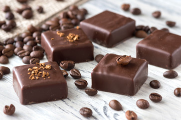 Chocolate sweets with coffee beans on a white wooden table. Candies bird's milk. Selective focus