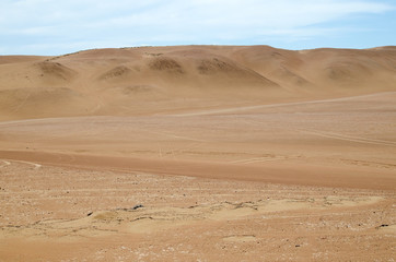 Fototapeta na wymiar Sands of the desert under bright blue sky with few clouds
