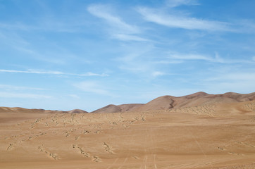 Fototapeta na wymiar Sands of the desert under bright blue sky with few clouds