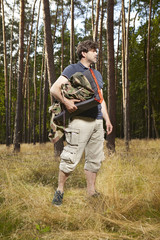 Man in wild forest going to hang hammock bed on trees