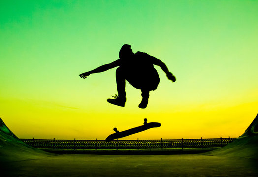 Young skateboarder does the trick on a bright green background - Powered by Adobe