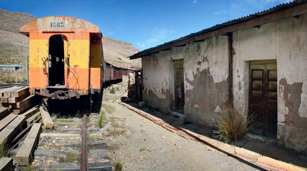Fototapeta na wymiar The abandoned railway wagons with damaged warehouse buildings