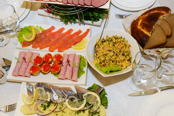 Dinner food table - top view. A delicious hearty meal of gourmet. Many dishes with appetizers on a white tablecloth. European cuisine for consumers.