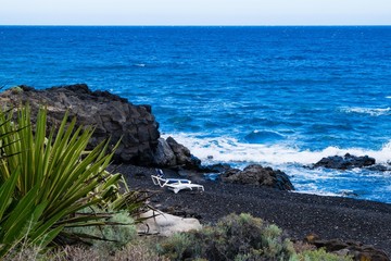 Black sand volcanic beach with sunbeds in Tenerife, Canary islands, Spain