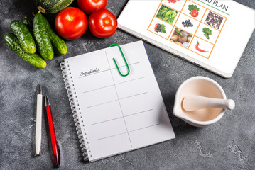Notebook, Vegan menu and digital tablet on wooden table