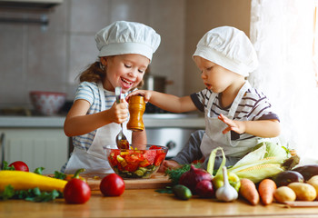 Alimentation équilibrée. Des enfants heureux préparent une salade de légumes dans la cuisine