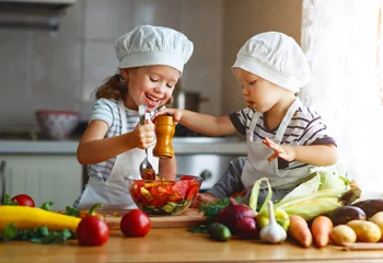 Crédence de cuisine en verre imprimé Cuisinier Alimentation équilibrée. Des enfants heureux préparent une salade de légumes dans la cuisine