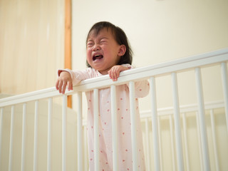 Baby girl crying in cot bed © M-image