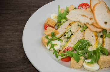 Caesar salad in a white plate on a wooden background