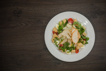 Caesar salad in a white plate on a wooden background