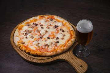 Hot piece of pizza with melted cheese on a rustic wooden table and beer
