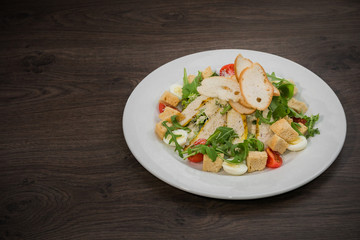 Caesar salad in a white plate on a wooden background