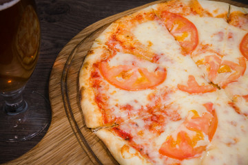 Hot piece of pizza with melted cheese on a rustic wooden table