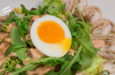 Salad with egg and mushrooms on a white plate and a wooden background