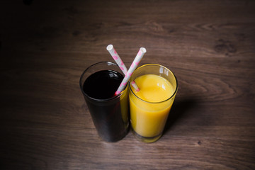 Two fresh glasses of juice with a straw