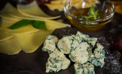 Cheese mix with honey and grapes on a stone background