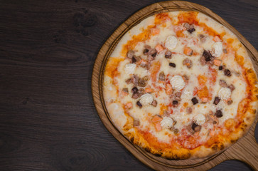 Hot piece of pizza with melted cheese on a rustic wooden table