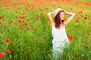 Naklejka na ściany i meble A happy woman in the field of red poppies
