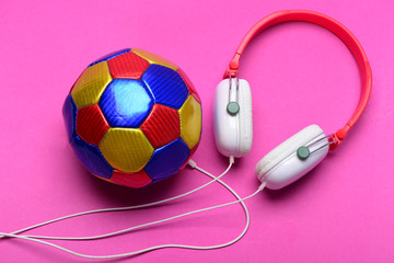 Modern earphones and football isolated on pink background