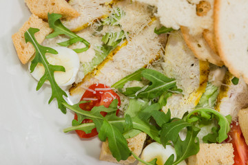 Caesar salad in a white plate on a wooden background