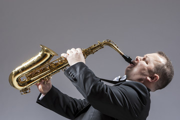 Obraz na płótnie Canvas Music Concepts. Full Length Portrait of Caucasian Mature Expressive Saxophone Player Playing the Instrument Against White Background.
