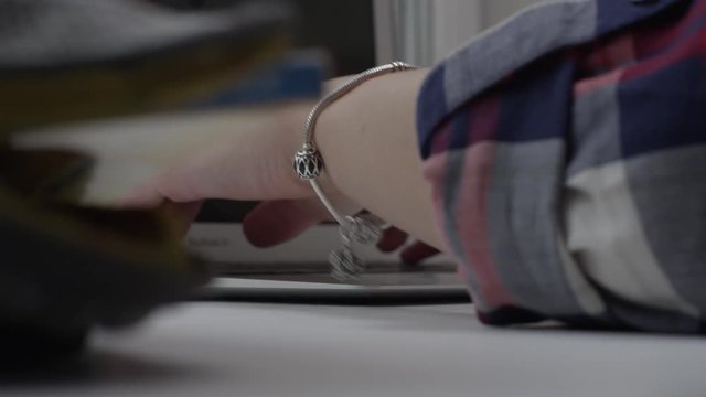 Close up of working hands on laptop on panorama window. Woman working on laptop on the windowsill