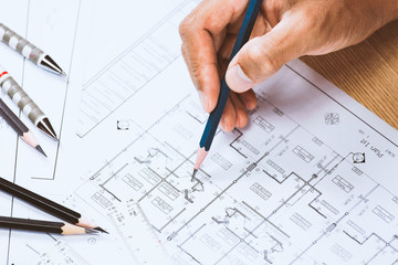Close-up of person engineer hand drawing plan on blue print with architect instrument at office desk.