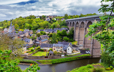 Naklejka premium Beautiful view of scenic narrow alley with historic traditional houses and cobbled street in an old town of Dinan with blue sky and clouds. Brittany (Bretagne), France