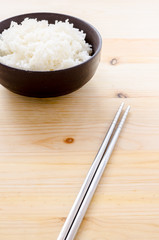 Rice in the black bowl on wood table background