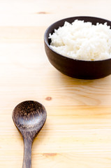Rice in the black bowl on wood table background