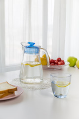 water with fruit, lemon and ice，near the window，bread
