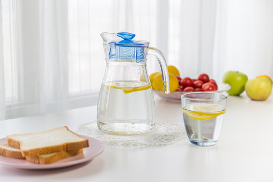 water with fruit, lemon and ice，near the window，bread