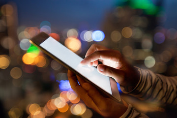 hand using digital tablet on night beauty light bokeh in city