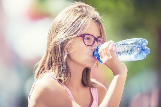 Young girl drinking fresh water on a hot summer day