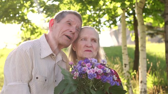 Portrait of elderly grandparents in a Sunny Park. Happy loving caring senior couple outdoors.