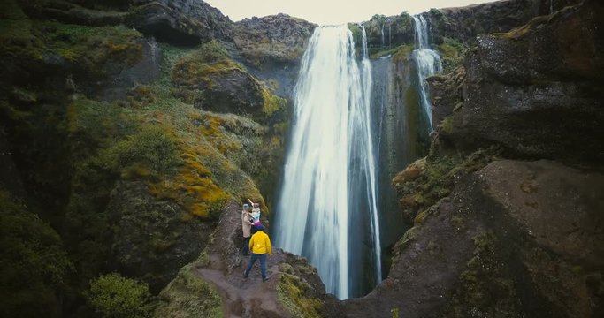 Aerial view of the group of tourists enjoying the view of Gljufrabui waterfall in Iceland. Friends happy after hiking.