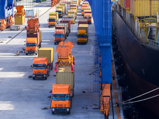Port operation loading container onboard.The trucks is queuing for loading containers to the vessel by port crane.