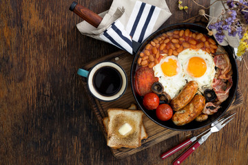 Full English breakfast with cup of coffee on wooden background