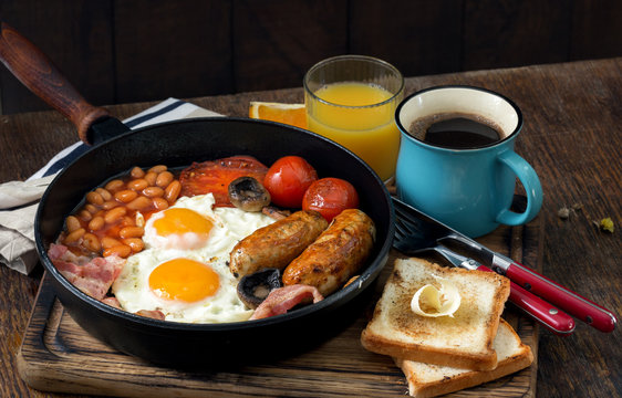 English breakfast on wooden table with coffee and orange juice