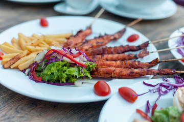 Potato fries with fry prawns, lettuce salad. Isolated over wooden background