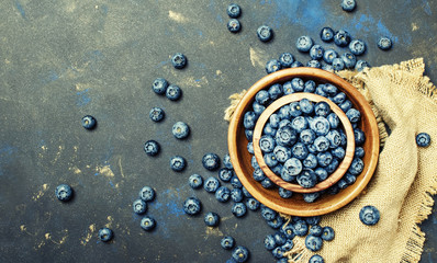 Fresh blueberries in a wooden bow on dark background, top view