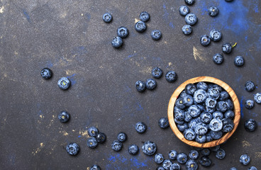 Blueberries in a wooden bowl, fod background, top view