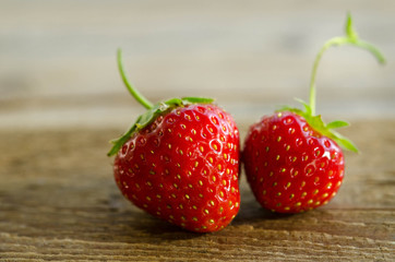 two strawberries on a wooden table