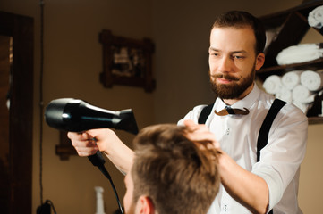 Master cuts hair and beard of men in the barbershop