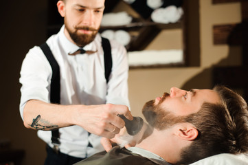 Master cuts hair and beard of men in the barbershop