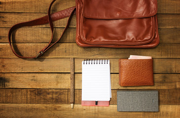 Notepaper, pencil, leather bag, wallet, money, mobile phone and equipment  on wooden background.