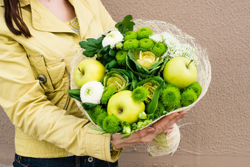 woman received trendy original greenery bouquet made with green and white flowers, apples wrapped in paper. For Valentines Day, Birthdays and Mothers Day