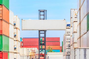 Forklift truck lifting cargo container in shipping yard or dock yard against blue sky cloudy with cargo container stack in background for transportation import, Export and logistic industrial concept